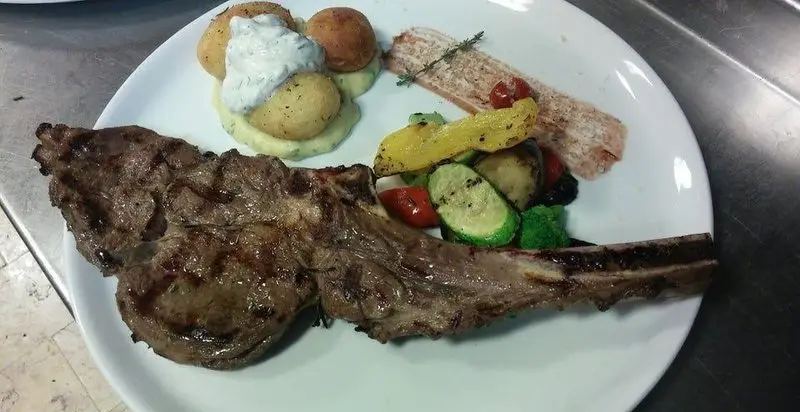 بشقاب غذای لذیذ رستوران فرسکا شامل دنده کبابی، ماهی سالمون گریل شده، سیب زمینی و سبزیجات تازه. یک انتخاب عالی برای ناهار یا شام.