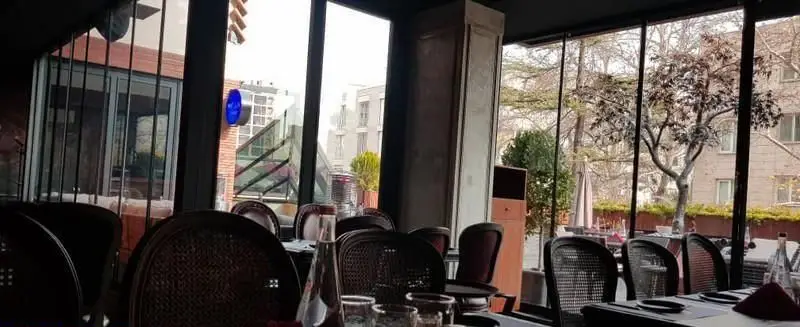 نمایی از فضای داخلی کافه رستوران مونلانژ، دارای پنجره‌های وسیع و نورگیر با منظره‌ای دلپذیر از درختان و محیط شهری بیرون.