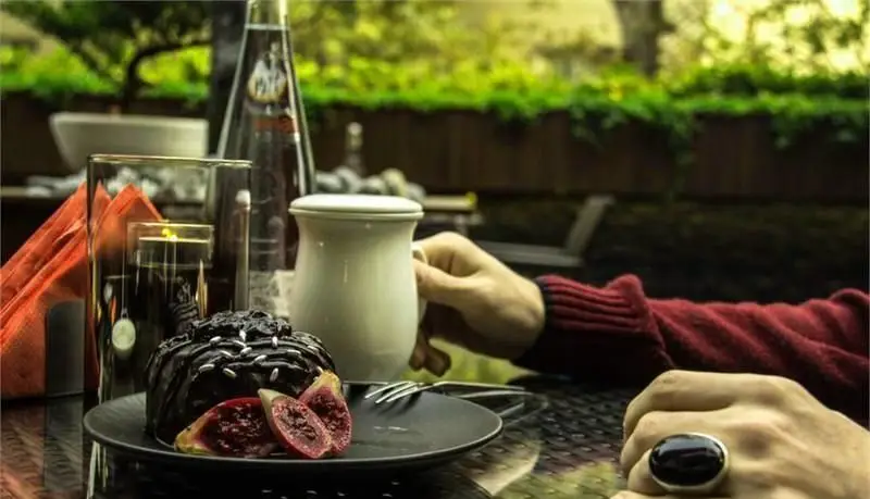 دسر کیک شکلاتی مجلل با میوه‌ در کافه رستوران مونلانژ. لذت یک عصرانه فراموش‌نشدنی در فضای سبز و آرامش‌بخش همراه با نوشیدنی.