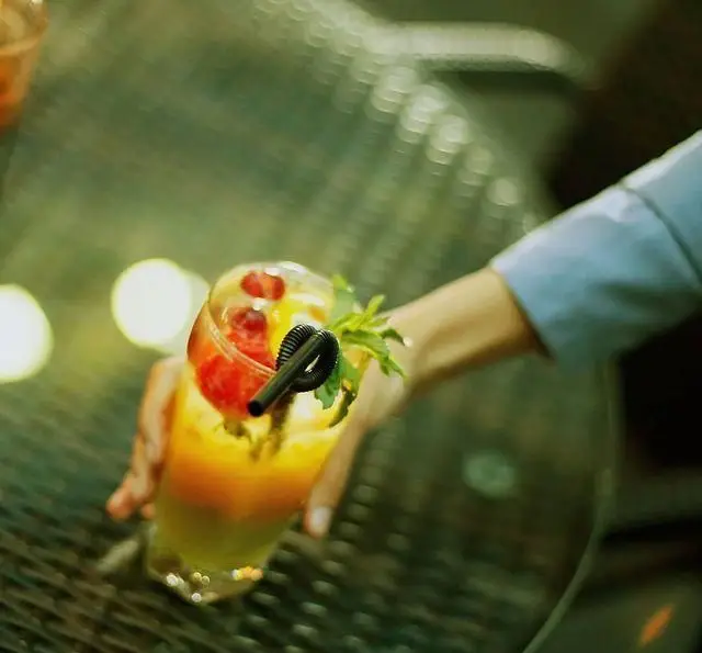 نوشیدنی خنک و میوه‌ای (مانند کوکتل) با تزئین نعناع و توت فرنگی در دست، تجربه‌ای دلنشین در کافه رستوران مونلانژ.