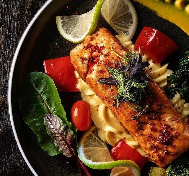 سالمون گریل شده با سس مخصوص، پوره سیب زمینی، سبزیجات تازه و لیمو. غذایی لذیذ از کافه رستوران مونلانژ.