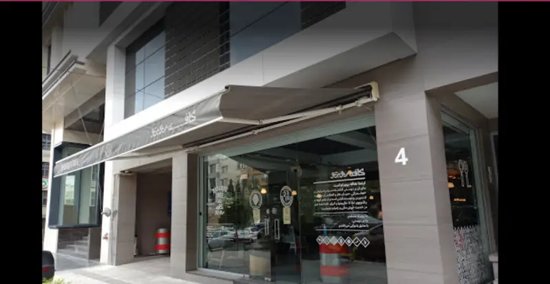 نمای بیرونی کافه روبرتو، یک کافی شاپ مدرن و شیک با سایبان طوسی، ورودی شیشه‌ای و دکوراسیون جذاب. بهترین مکان برای اوقات خوش.