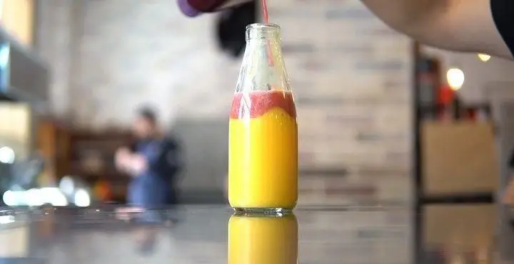 نوشیدنی میکس میوه لایه‌ای و جذاب در کافه روبرتو، آماده شده با آبمیوه‌های تازه زرد و قرمز، انتخابی عالی برای یک روز گرم.