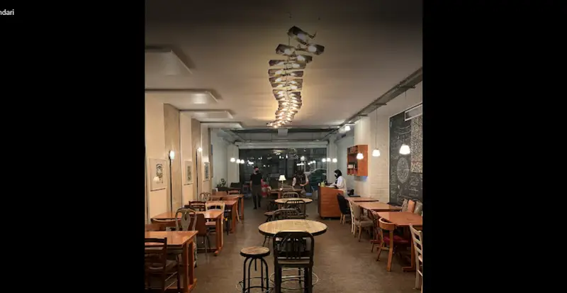تصویری از فضای داخلی کافه روبرتو، دکوراسیون دلنشین با میز و صندلی‌های چوبی، لوستر خاص و نورپردازی گرم برای پاتوقی دنج و آرام.