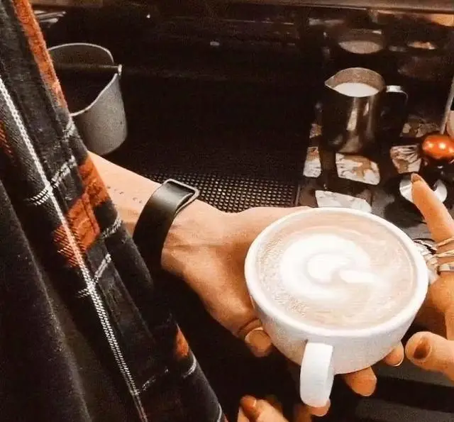 باریستای کافه مانا یک فنجان لاته آرت زیبا را به مشتری ارائه می‌دهد، نمادی از قهوه با کیفیت و تجربه‌ای دلنشین در کافه مانا.