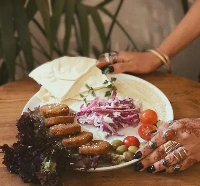 بشقاب فلافل وگان کافه مانا با نان پیتا، سالاد کلم بنفش، زیتون و گوجه گیلاسی. یک غذای سالم و خوشمزه.