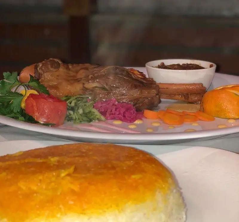 غذای اصلی لذیذ رستوران ماه و مهر شامل گوشت بره، برنج ته دیگ و مخلفات متنوع. تجربه‌ای خوشمزه از غذاهای اصیل ایرانی.