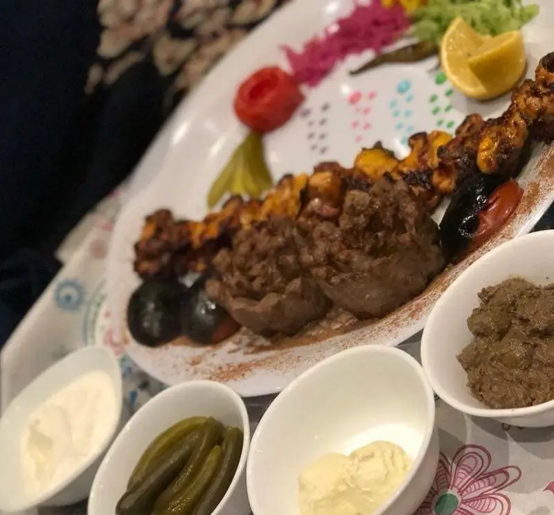 سینی کباب ماه و مهر: ترکیبی از کباب کوبیده و جوجه کباب به همراه گوجه کبابی، لیمو، و انواع مخلفات (خیارشور، ماست، دیپ) در فضایی دلنشین