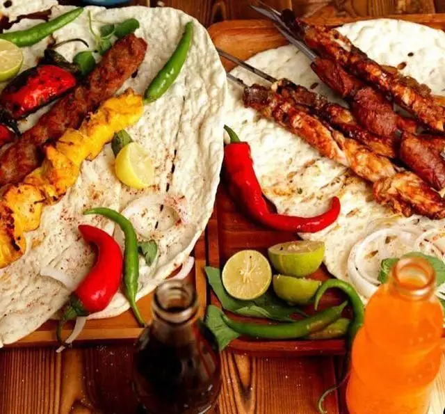 تصویری از سینی‌های اشتهاآور کباب جگر، قلوه، کوبیده و مرغ جگر سرای دل و قلوه با نان، لیمو و فلفل تازه، یک تجربه غذایی ایرانی اصیل و خوشمزه.