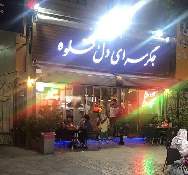 جگر سرای دل و قلوه در شب، تابلوی نئونی روشن و مشتریانی در حال لذت بردن از جگر و کباب در فضای داخلی و بیرونی رستوران.