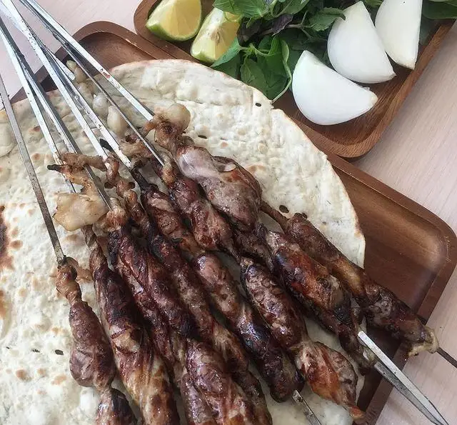 سیخ‌های کباب جگر، دل و قلوه داغ و لذیذ، سرو شده روی نان تازه، همراه با سبزیجات معطر، لیمو و پیاز در جگر سرای دل و قلوه.