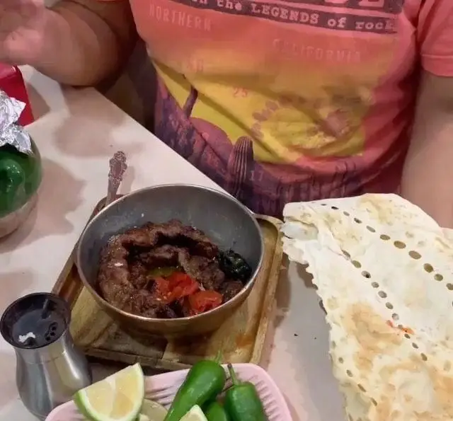 تصویر غذای لذیذ جگر و دل در کاسه مسی با گوجه و فلفل، کنار نان تازه و لیمو. تجربه طعم اصیل ایرانی در جگر سرای دل و قلوه.