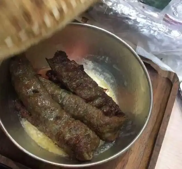 کباب‌های داغ و لذیذ جگر سرای دل و قلوه، در ظرف فلزی براق، غوطه ور در کره داغ و آماده سرو با نان تازه و ترد.