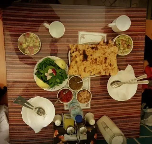 میز غذای سنتی دیزی سرای ۱۱۰ شامل نان تازه، سبزی خوردن، سالاد و مخلفات متنوع؛ آماده برای یک تجربه غذایی اصیل و دلنشین.