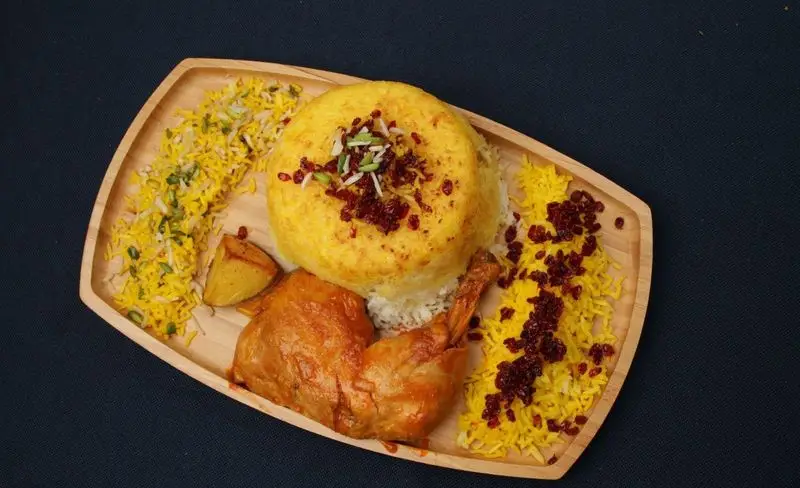 ته چین مرغ مجلسی با کته زعفرانی، زرشک و خلال پسته، همراه با ران مرغ و سیب زمینی از کترینگ بزرگ کیبو. غذای سنتی ایرانی