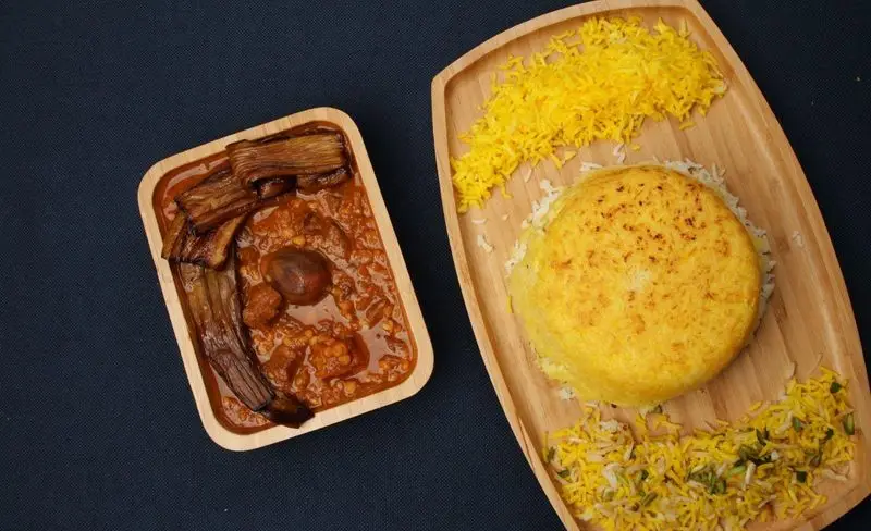 غذای لذیذ و اصیل ایرانی کترینگ کیبو شامل خورش قیمه بادمجان با گوشت و بادمجان‌های سرخ شده، در کنار برنج زعفرانی معطر با ته دیگ طلایی و دورچین.