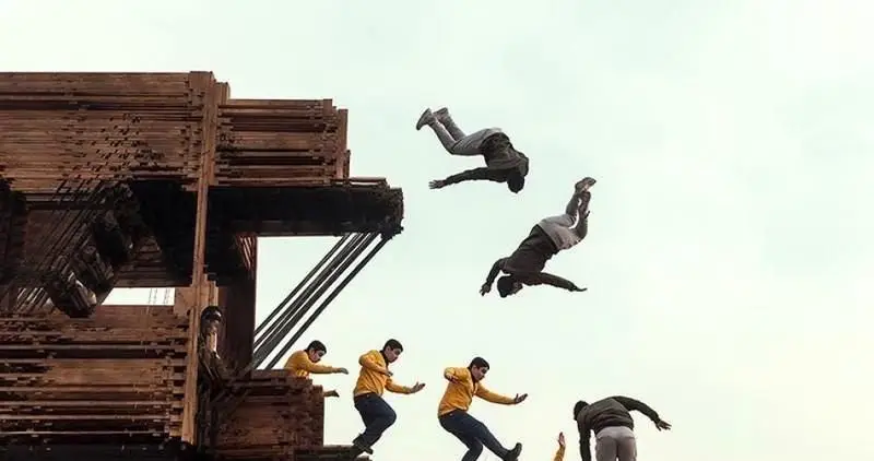 تصویری پویا از چندین جوان در حال اجرای حرکات ورزشی آکروباتیک و پرش‌های هیجان‌انگیز در فضای وسیع و جذاب بام لند تهران.