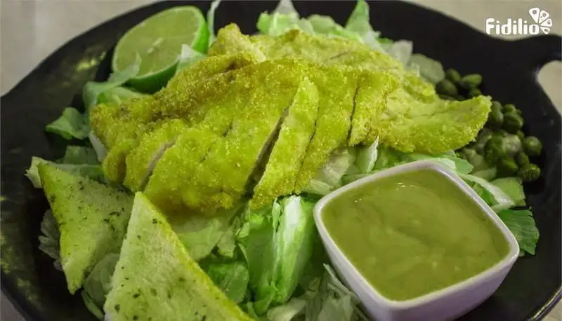 سالاد سینه مرغ ترد با روکش سبز، کاهو تازه، برش‌های لیمو و سس سبز ویژه رستوران فرنگی شانلی. غذایی سالم و خوشرنگ.