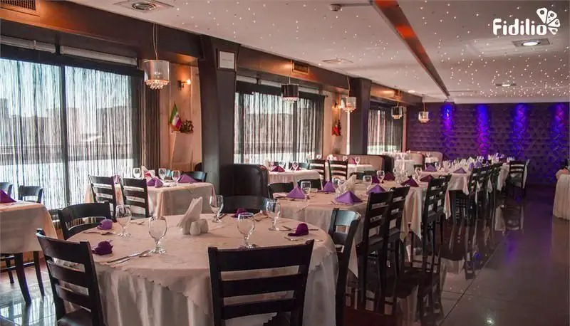 نمای داخلی دلباز و مدرن رستوران فرنگی شانلی، با چیدمان شیک میز و صندلی‌ها، نورپردازی ستاره‌ای سقف و دیوار بنفش.