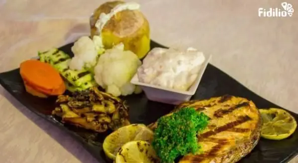 غذای کامل و سالم رستوران فرنگی شانلی: ماهی سالمون گریل شده با لیمو، سیب زمینی تنوری، کلم بروکلی و گل کلم، همراه با سبزیجات گریل شده.