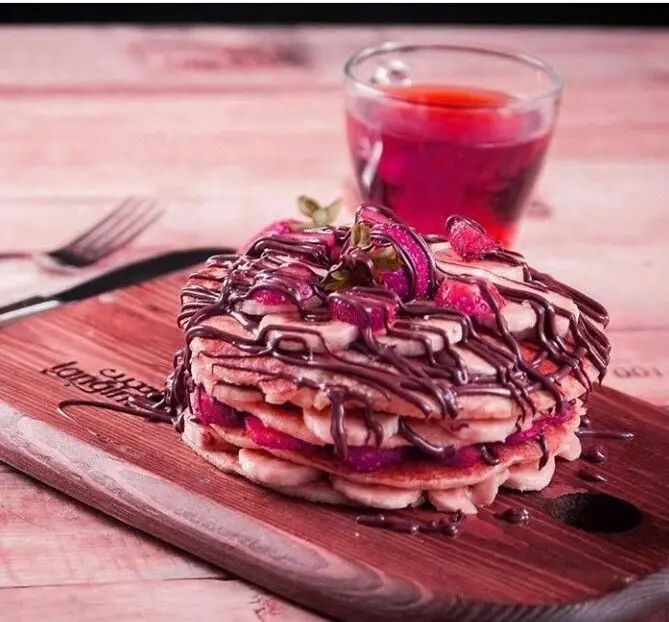 پنکیک‌های خوشمزه کافی شاپ لانجین با موز، توت فرنگی و سس شکلات. ایده‌آل برای صبحانه یا دسر در Langin Coffee Shop.