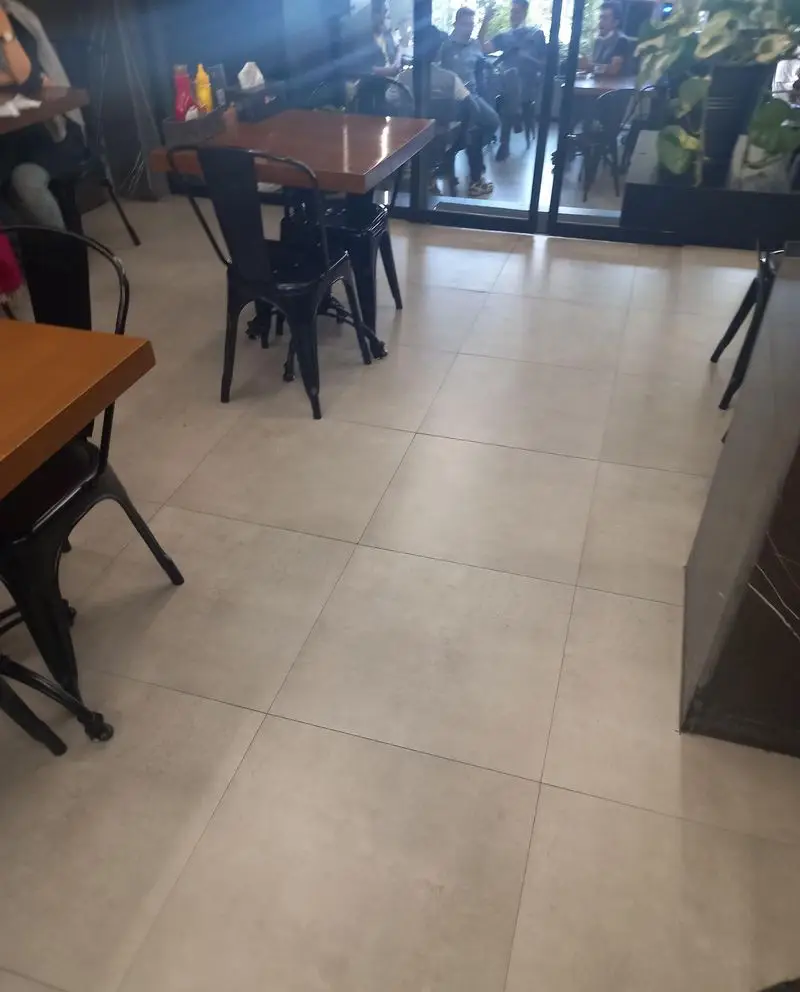 فضای داخلی دلباز و مدرن رستوران شیلا با چیدمان شیک میز و صندلی چوبی و فلزی، کفپوش روشن و نورپردازی طبیعی. مکانی ایده‌آل.