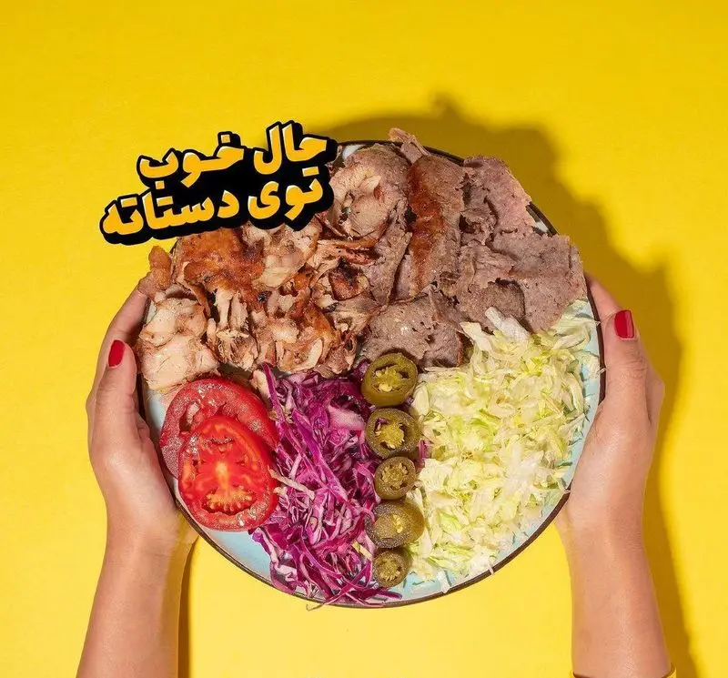 بشقاب کامل دونر میکس گوشت و مرغ داغ و تازه از دونر گاردن پاسداران در دستان. همراه با کلم، گوجه و هالوپینو. بهترین فست فود تهران.