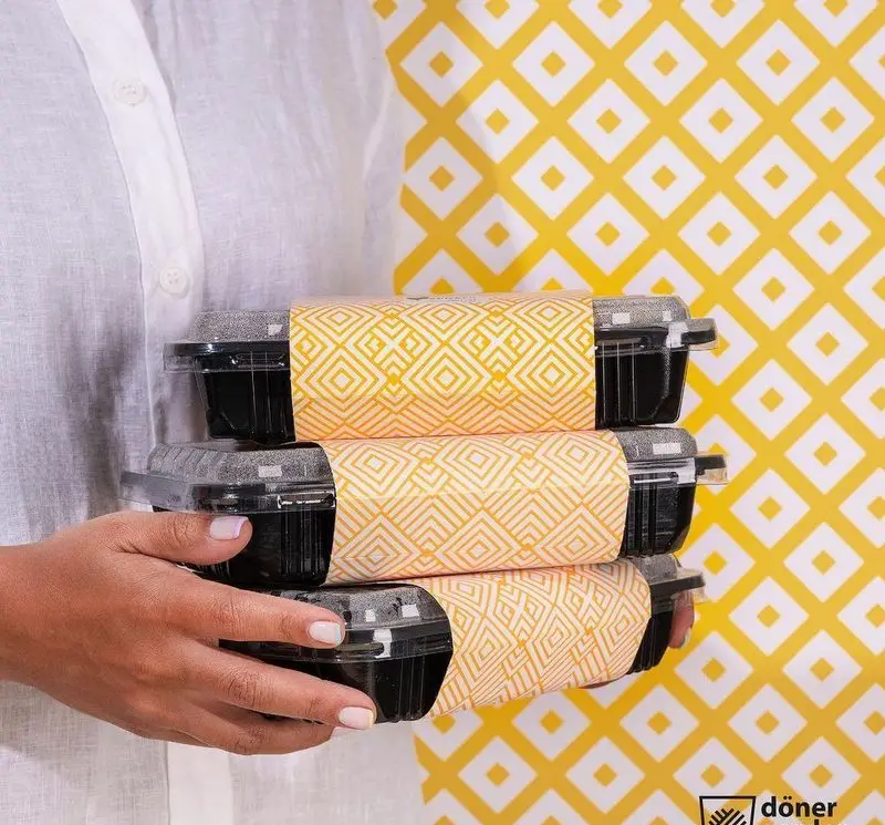 تصویری از بسته‌بندی غذای آماده فست فود دونر گاردن پاسداران: سه ظرف ساندویچ دونر با کاغذهای طرح‌دار زیبا.