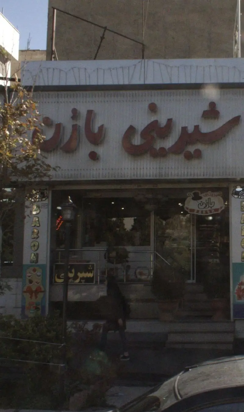 تصویر نمای بیرونی فروشگاه شیرینی بارُن، یک قنادی معروف با تابلوی بزرگ و واضح به زبان فارسی. ورودی شیشه‌ای این شیرینی‌فروشی مدرن و جذاب است.