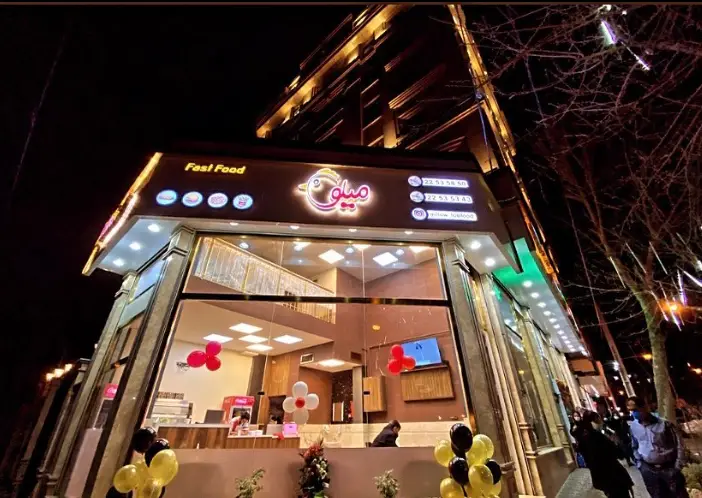 تصویر شب از نمای خارجی فست فود میلو با تابلوی روشن و طراحی داخلی مدرن، آماده پذیرایی از علاقه‌مندان به غذاهای سریع.