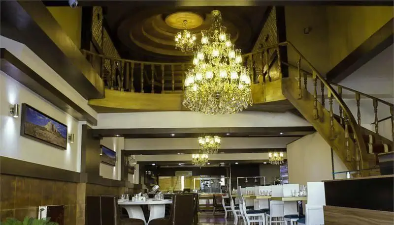 دکوراسیون داخلی شیک و لوکس رستوران ایرانی ناهید با لوستر بزرگ، پله چوبی زیبا و فضای دلنشین برای مشتریان.