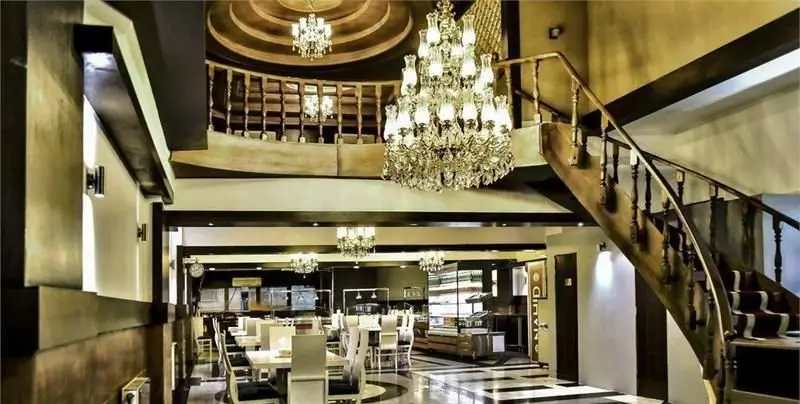 نمای داخلی شیک و بزرگ رستوران ایرانی ناهید، با لوستر کریستالی چشم‌نواز، پله‌های چوبی منحنی و فضای وسیع پذیرایی در دو طبقه.