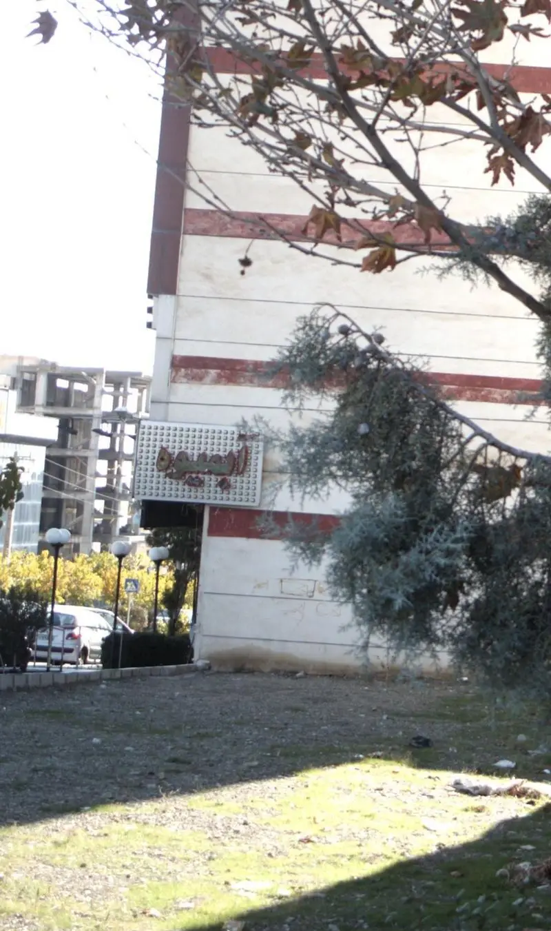 نمای بیرونی کسب و کار بستنی آبمیوه امیر، تابلوی بزرگ و مشخص آن، محوطه سرسبز و درختان پاییزی در یک روز آفتابی دلپذیر.