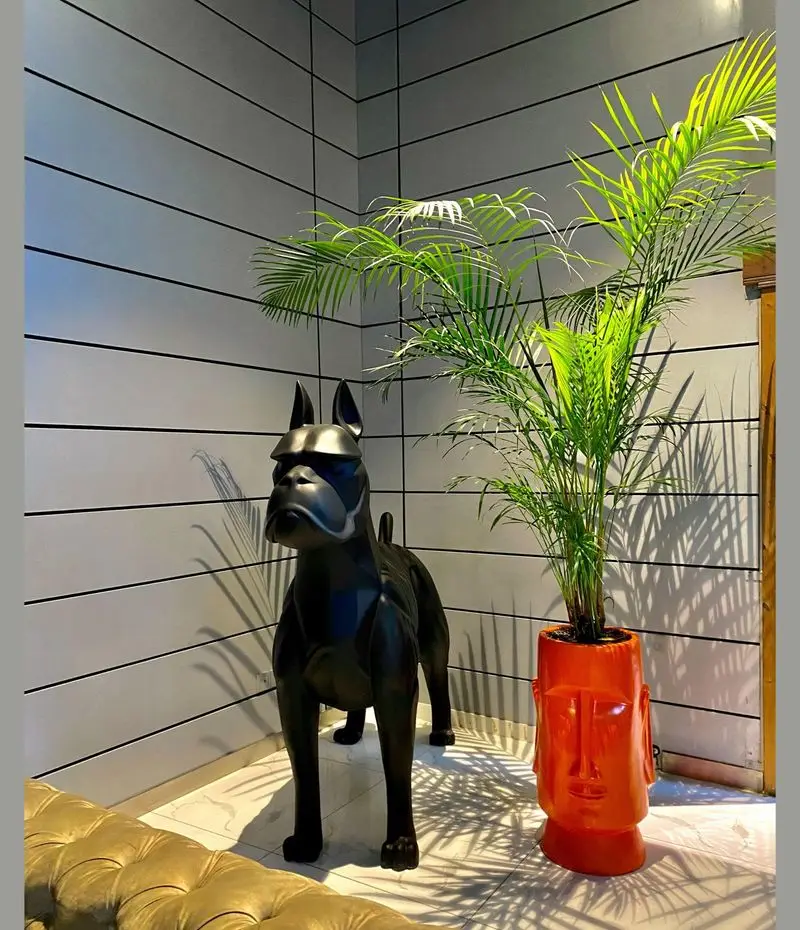 دکوراسیون داخلی کافه رستوران پلاس شیم با مجسمه سگ مدرن و گلدان سر انسان نارنجی، فضایی شیک و خاص برای مشتریان