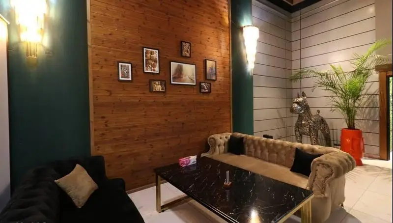 فضای داخلی دنج و مدرن کافه رستوران پلاس شیم با مبلمان راحتی، میز مرمری، دیوار چوبی و دکوراسیون شیک.