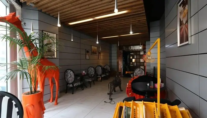 فضای داخلی مدرن کافه رستوران پلاس شیم با دکوراسیون منحصربه‌فرد، مجسمه زرافه نارنجی، صندلی‌های طرح گورخر و گیاهان سرسبز.