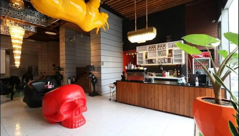 فضای داخلی مدرن و منحصربفرد کافه رستوران پلاس شیم با مجسمه زرد، جمجمه قرمز، میز بار شیک و محیط دلپذیر.