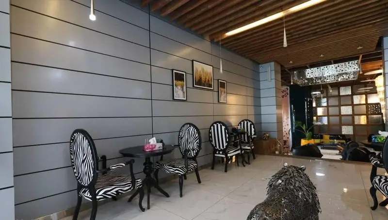 فضای داخلی کافه رستوران پلاس شیم با دکوراسیون مدرن، دیوار پنلی خاکستری، صندلی‌های شیک طرح گورخری و سقف چوبی. محیطی آرام و دلپذیر.