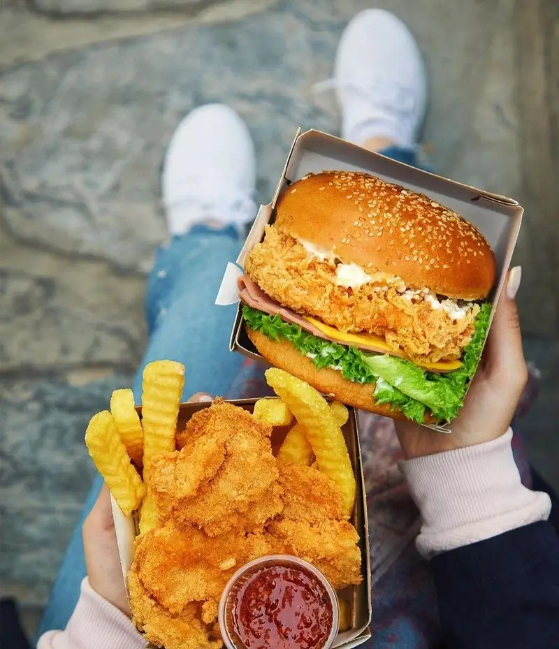 سفارش غذای خوشمزه از رستوران باروژ شامل یک برگر سوخاری کریسپی، تکه‌های مرغ سوخاری و سیب زمینی سرخ کرده ترد و طلایی.