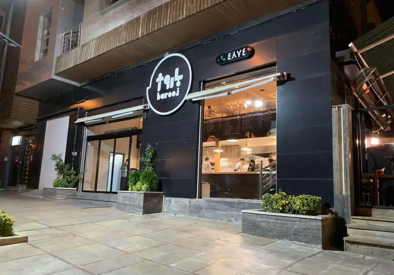 تصویری از نمای شبانه و مدرن رستوران و فست فود باروژ (Barooj) با تابلوی واضح، ورودی شیشه‌ای، و نورپردازی جذاب آماده پذیرایی از مشتریان.