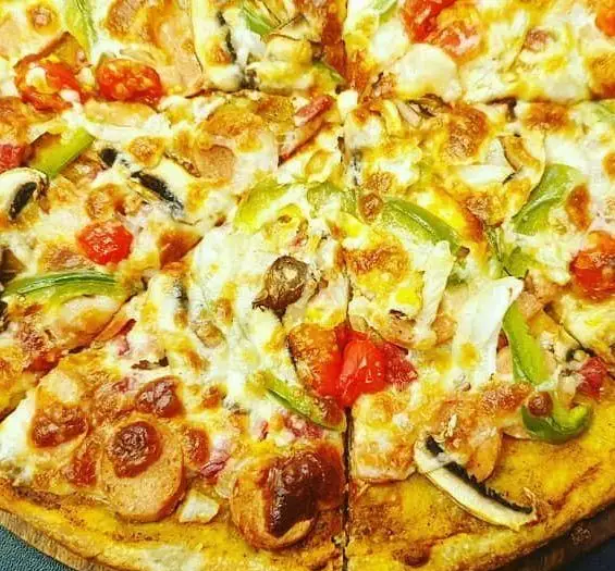 تصویر پیتزا رستوران باروژ، با پنیر آب شده طلایی، تکه‌های فلفل دلمه‌ای سبز، قارچ، گوجه و برش‌های سوسیس، بسیار اشتهاآور.
