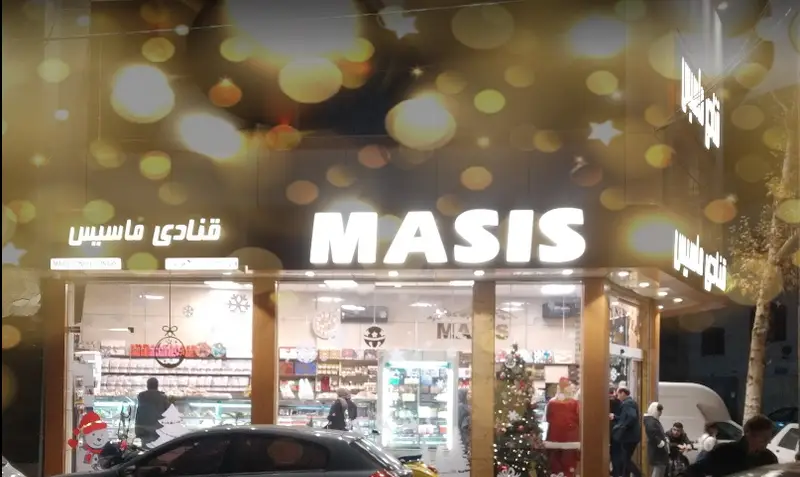 نمایی جذاب و شبانه از قنادی ماسیس با نورپردازی ویژه و دکور کریسمس. این شیرینی فروشی انواع کیک، دسر و شیرینی را عرضه می کند.