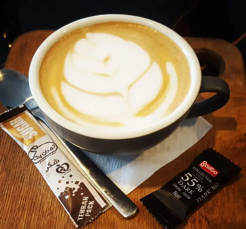 قهوه لاته با لته آرت برگ در فنجانی شیک، به همراه شکر تهران پک و شکلات دارک، تجربه دلپذیر در کافه و رستوران تراس لانژ.