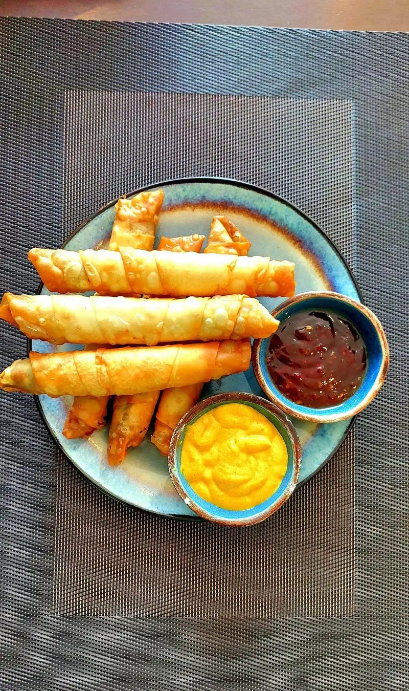 پیش غذاهای جذاب کافه و رستوران تراس لانژ: رول‌های طلایی سرخ شده با سس چیلی و سس کرمی زرد. غذایی لذیذ و خوش‌طعم.