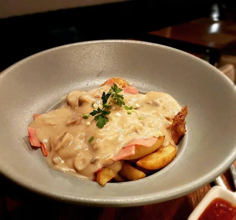 یک غذای گرم و لذیذ در کافه و رستوران تراس لانژ: سیب زمینی وجز طلایی، سس خامه ای قارچ و ژامبون، تزئین با جعفری.