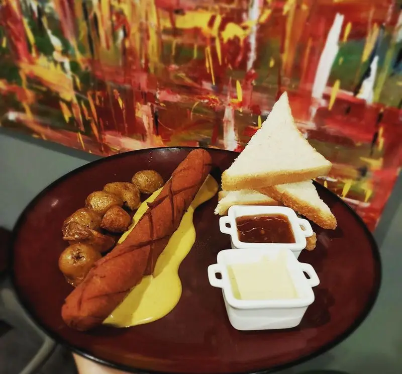 یک صبحانه یا وعده غذایی لذیذ در کافه و رستوران تراس لانژ: سوسیس گریل شده با سیب زمینی تنوری، نان تست و انواع سس.