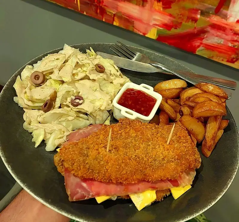سفارش لذیذ شنیتسل مرغ ژامبون و پنیر همراه سالاد کلم و سیب زمینی سرخ کرده در کافه و رستوران تراس لانژ.