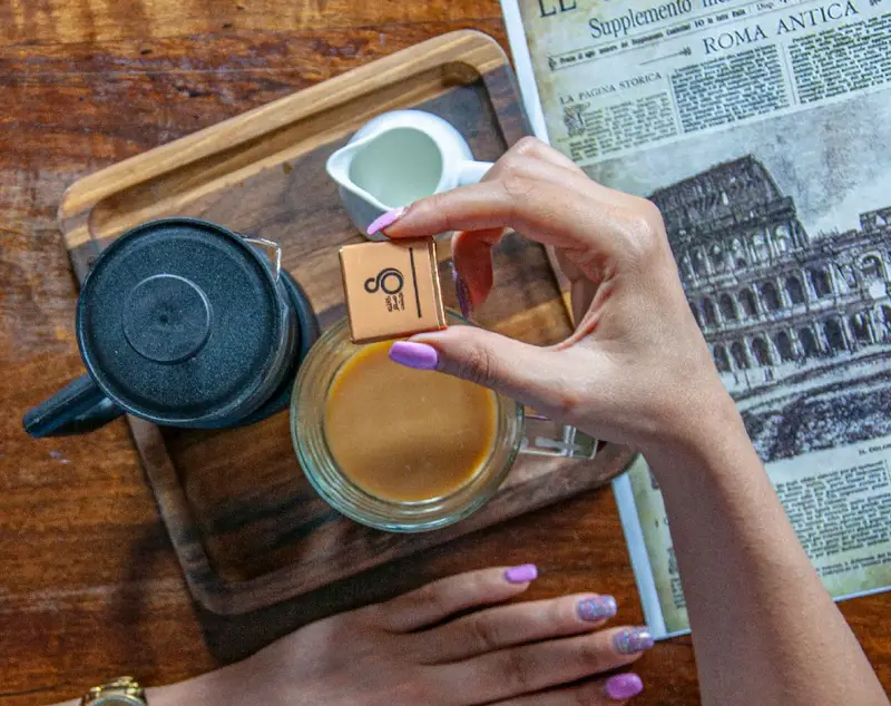 لحظه لذت‌بخش در کافه ۰۸: یک فنجان قهوه گرم در کنار شکلات برند ۰۸ و مطالعه روزنامه رومی، فضایی دلنشین برای شروع روز.