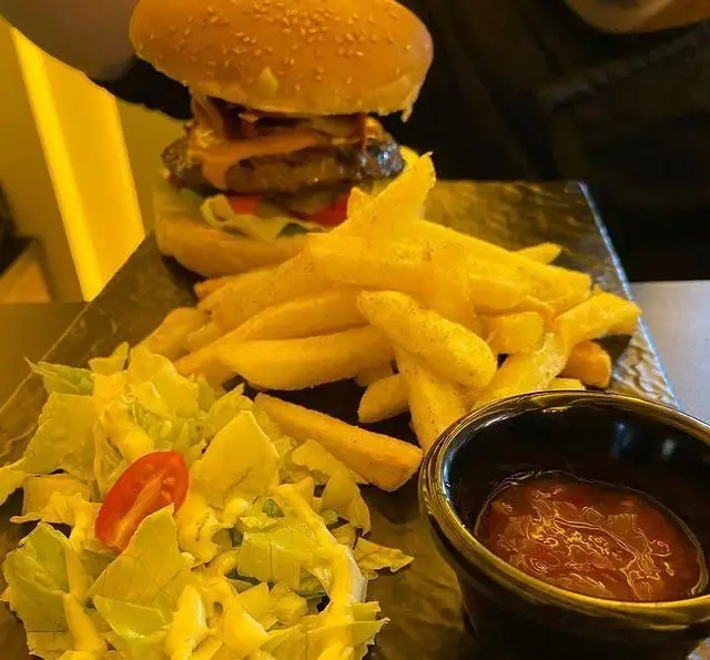 همبرگر دست‌ساز کافه برلین با سیب‌زمینی سرخ کرده طلایی، سالاد تازه و سس مخصوص؛ تجربه‌ای دلپذیر از غذای با کیفیت.