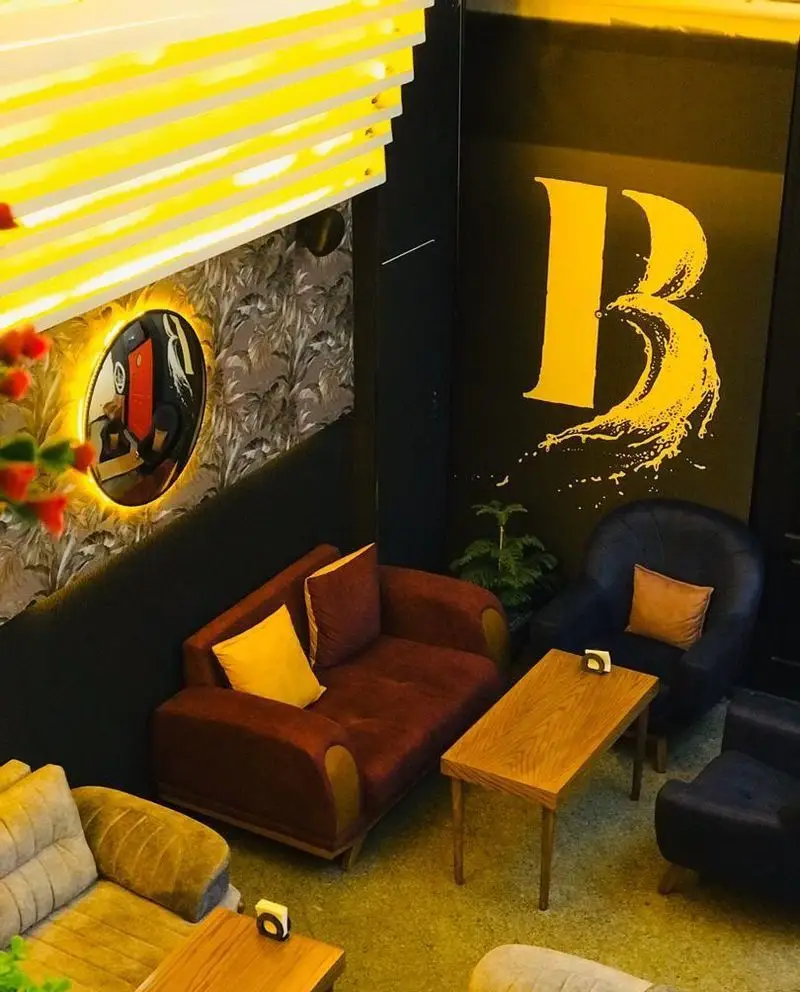 فضای داخلی کافه برلین با دکوراسیون مدرن، مبلمان راحت شامل کاناپه‌ها و صندلی‌های شیک، و نورپردازی گرم و دلنشین.